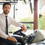 Chauffeur professionnel souriant au volant pour un service de location d’autocar avec chauffeur.
