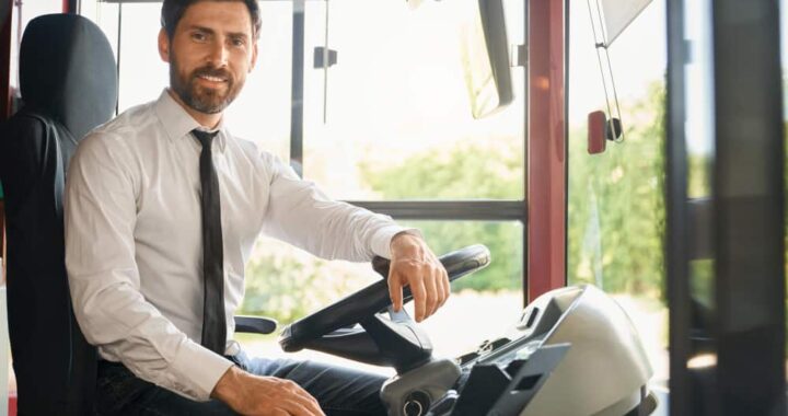 Chauffeur professionnel souriant au volant pour un service de location d’autocar avec chauffeur.