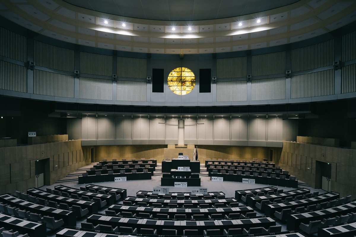 Salle de conférence avec amphithéâtre, chaises, tables, podium, lumière, mur courbe Salle de conférence avec amphithéâtre, chaises, tables, podium, lumière, mur courbe