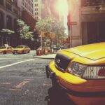Taxis jaunes circulent sur une avenue urbaine ensoleillée