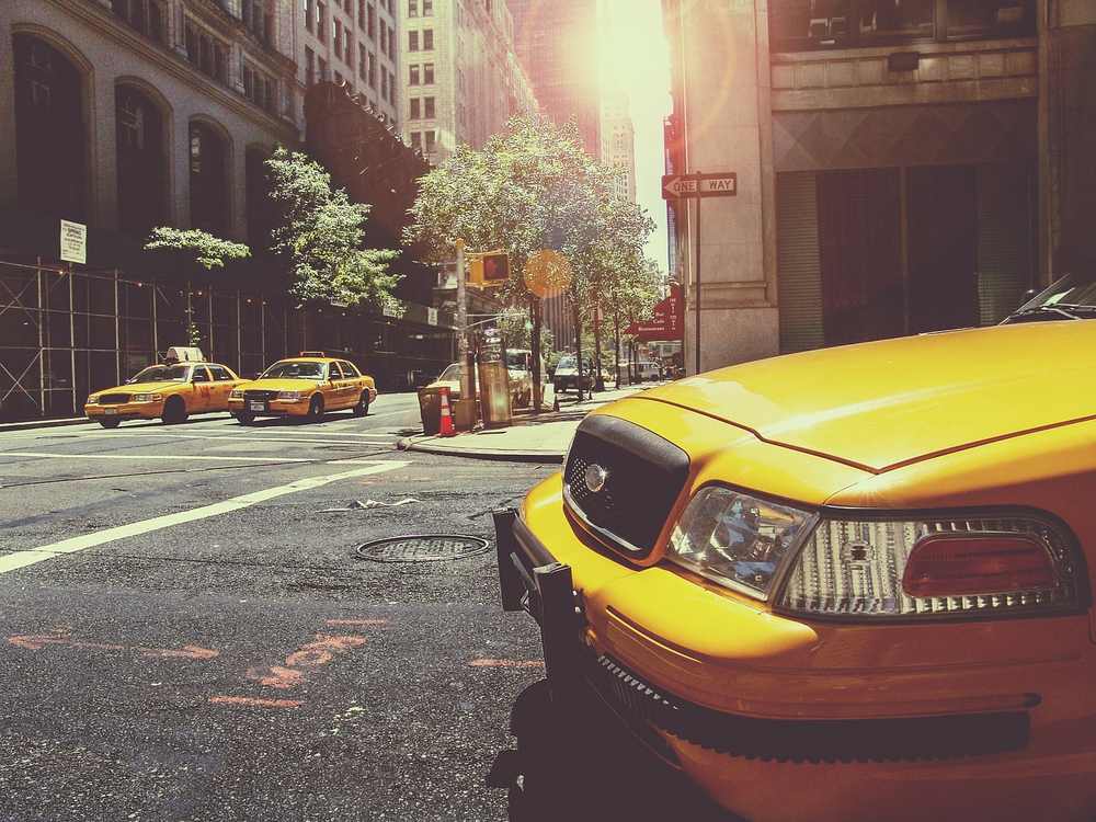 Des taxis jaunes circulent sur une rue de ville ensoleillée