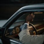 Un homme dans une voiture tient la vitre du véhicule