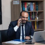 Homme d'affaires en costume téléphonant à son bureau avec ordinateur portable et documents