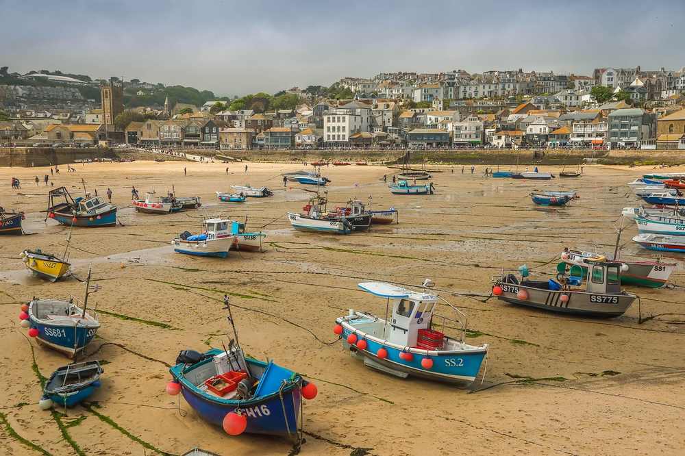 Bateaux de pêche échoués sur le sable, ville côtière en arrière-plan
