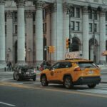 Taxi jaune et voiture noire devant un édifice monumental avec colonnes