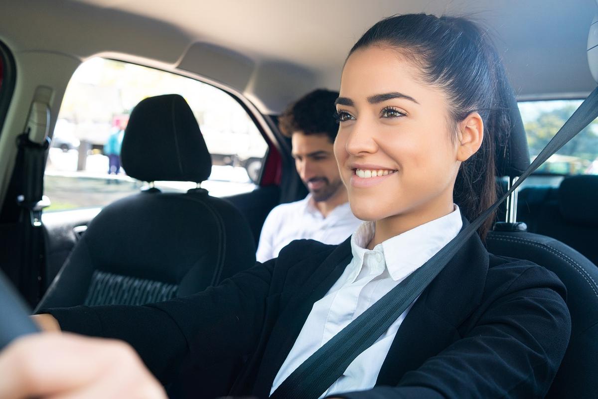 Une femme sourit au volant, un homme à l'arrière, tous deux attachés Une femme sourit au volant, un homme à l'arrière, tous deux attachés