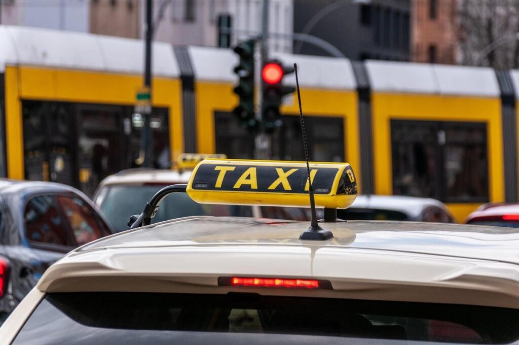 Un taxi stationné sous un panneau jaune à feu rouge