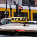 Un taxi stationné sous un panneau jaune à feu rouge