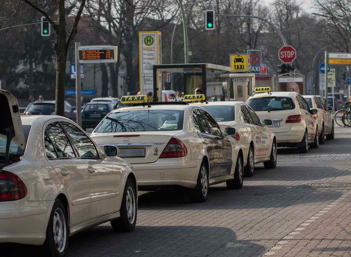 Une rangée de taxis blancs s’arrête au feu rouge d’une intersection Une rangée de taxis blancs s’arrête au feu rouge d’une intersection